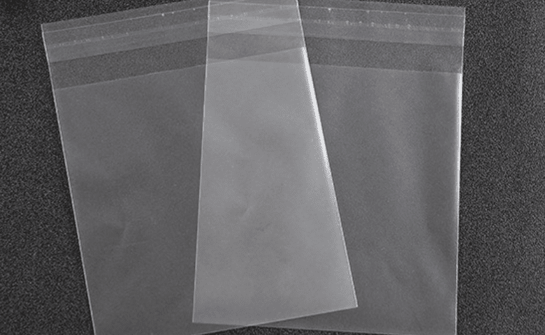Three clear, empty plastic bags with adhesive strips at the top, arranged in a fan shape on a dark background.