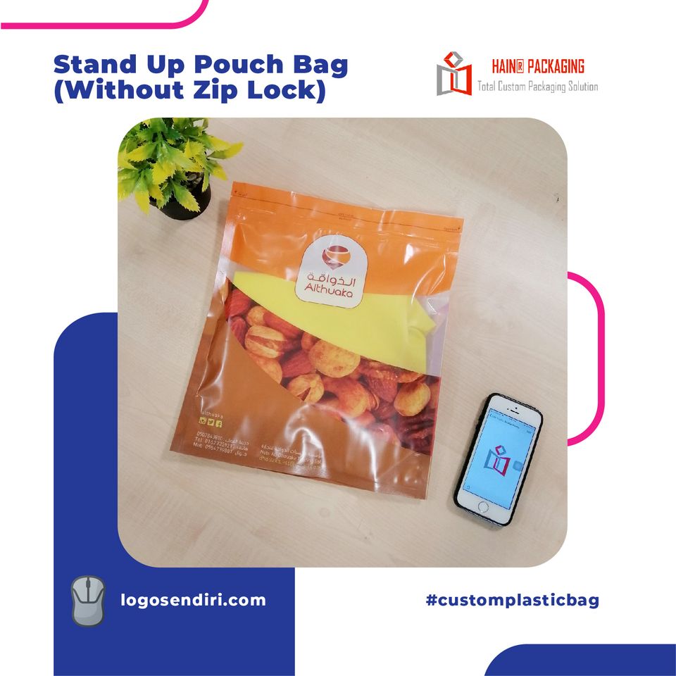 A stand-up pouch filled with dried fruit sits on a light wooden surface next to a smartphone, with a small potted plant in the corner.