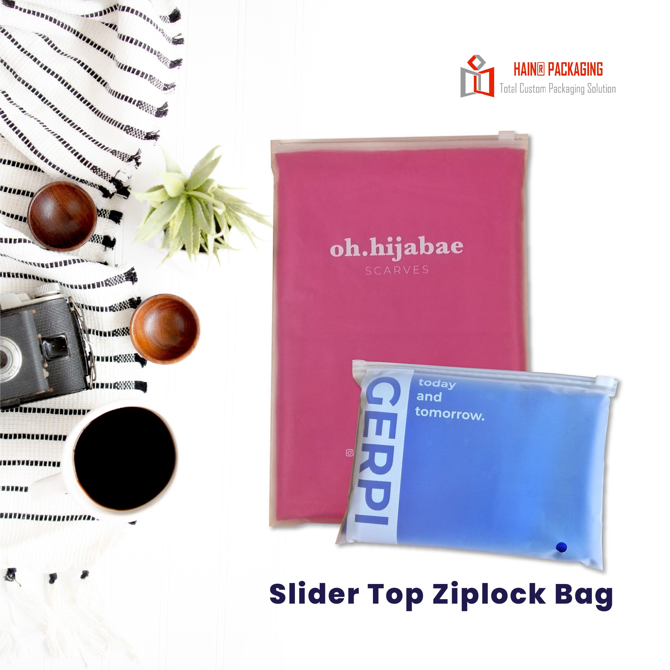 Two slider top ziplock bags, one pink and one blue, displayed next to a coffee cup, camera, and plant.