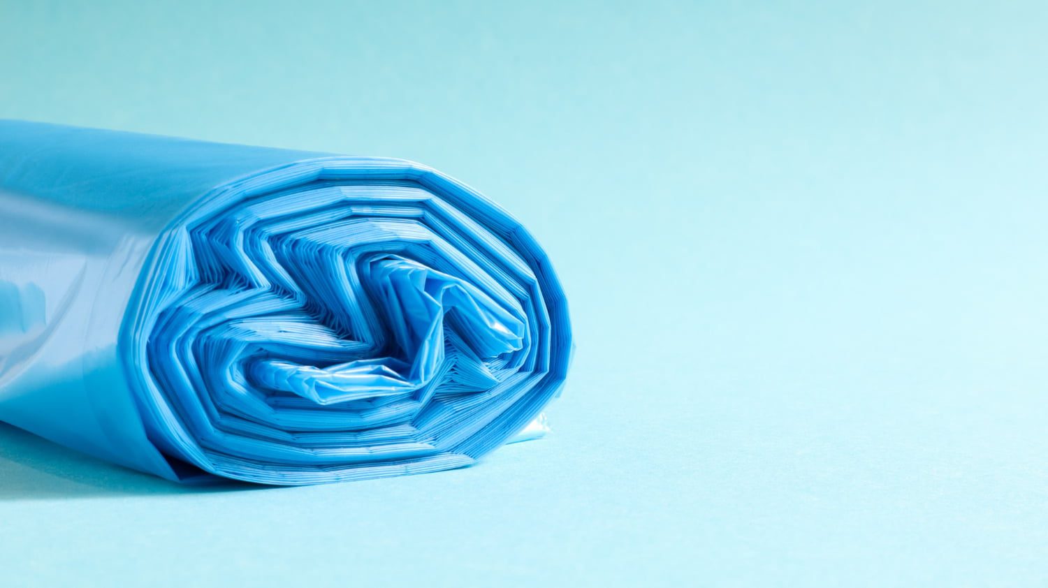 A roll of blue plastic bags on a light blue background.