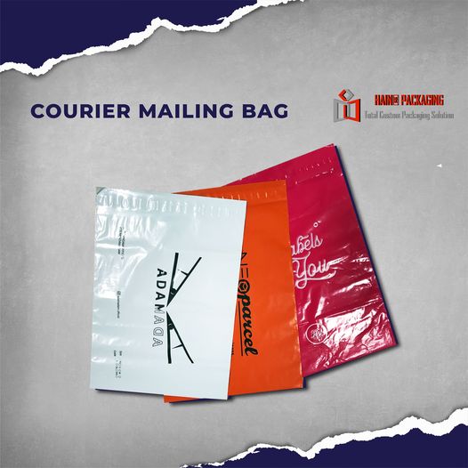 Three plastic courier mailing bags in white, orange, and pink stacked on a grey background.