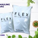 Two white plastic mailing bags with the text FLEX BE LIMITLESS printed on them, displayed on a white wooden surface with potted plants.