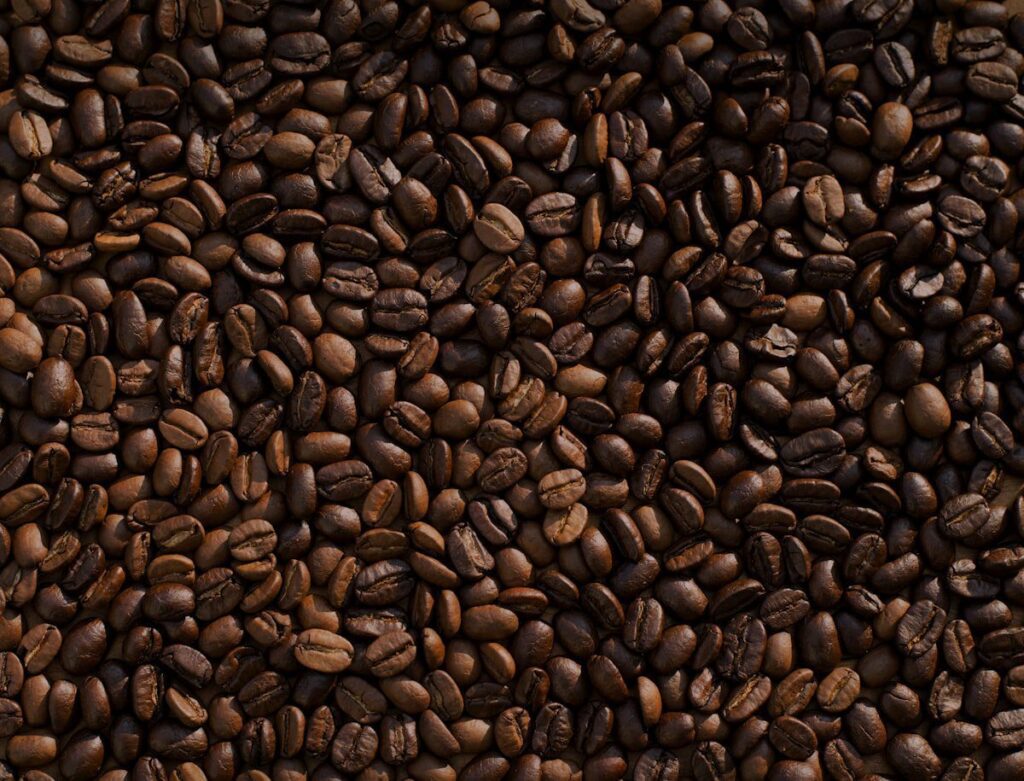 A close-up, top-down view of a large pile of roasted brown coffee beans.