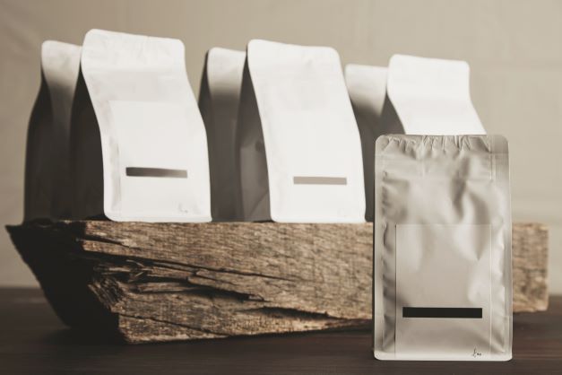 Several white, rectangular, sealed pouches arranged on a piece of rough-hewn wood.