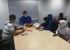 Four people wearing face masks sitting around a conference table in an office.