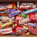 A top-down view of a cardboard box packed with various branded chocolate and cereal bars.